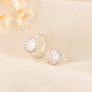 Eleganti orecchini a cerchio halo in argento con zircone tondo su sfondo di lino