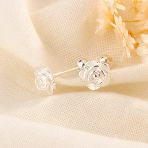 Macro shot of silver rose stud earrings with screw ball backs on textured fabric
