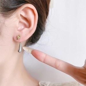 Close-up of dual-tone asymmetric teardrop earrings in gold and silver plating