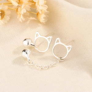 Minimalist cat stud earrings with tassel chain and bell on beige textured fabric