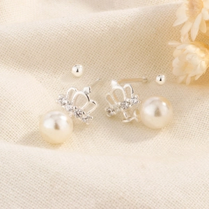 Boucles d'oreilles couronne en perles et cristaux sur fond de lin texturé