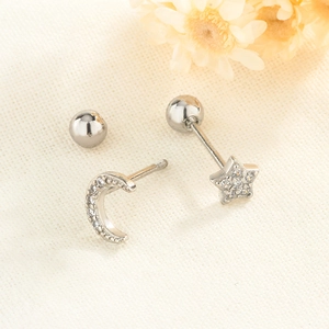 Detailed view of asymmetric star and moon stud earrings with zircon inlay on linen