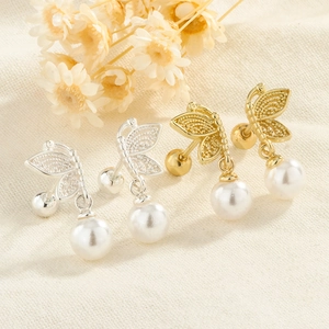 Detailed macro view of hollow butterfly earrings with white pearls and screw backs