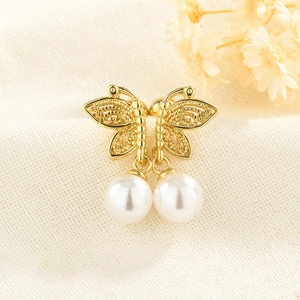 Macro shot of gold butterfly earrings with pearls on natural linen texture