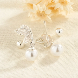 Detail of silver butterfly earrings with white pearls and screw back ball closure