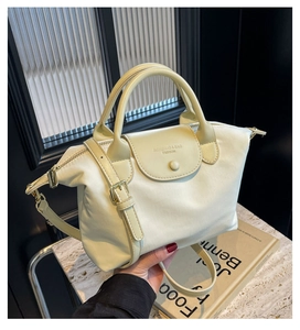 Detailed close-up of light beige nylon dumpling bag with premium leather handle and strap