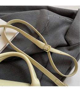 Detail of adjustable pale yellow leather shoulder strap with golden metal buckle