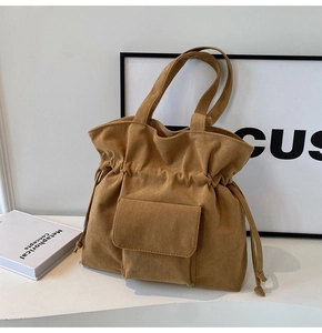 Close-up of brown corduroy tote bag featuring drawstring closure and front flap pocket