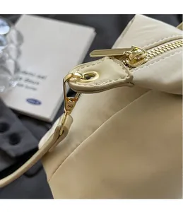 Detailed close-up of golden metal hooks and precise stitching on a beige oxford cloth bag