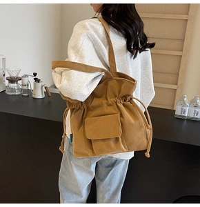 Brown corduroy shoulder bag with drawstring closure and front pocket detail