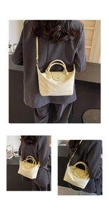 Detail of beige nylon crossbody bag with green leather handle and brand embossed flap