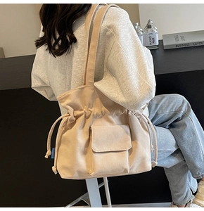Detailed view of beige corduroy drawstring shoulder bag with side pockets and texture
