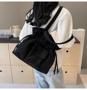 Detail of black corduroy drawstring backpack showing vertical texture and pocket