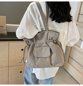 Detail of khaki corduroy drawstring tote bag with flap pocket shown on female model