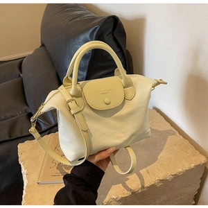 Detail of cream nylon handbag showing double handles and adjustable shoulder strap
