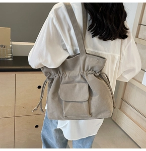 Detail of khaki corduroy tote bag with drawstring closure and front pocket on shoulder