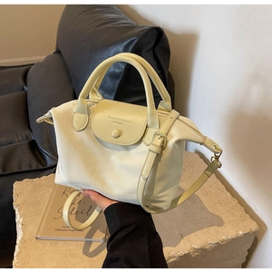 Detail of light beige oxford handbag with leather stitching on a stone display