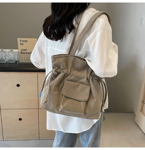 Detail of khaki corduroy tote bag featuring drawstring closure and front flap pocket