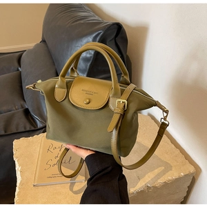 Detail of olive green nylon tote bag with leather flap and gold metal buckle accents