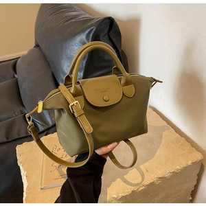 Detail of olive green nylon handbag featuring snap closure and textured leather handles