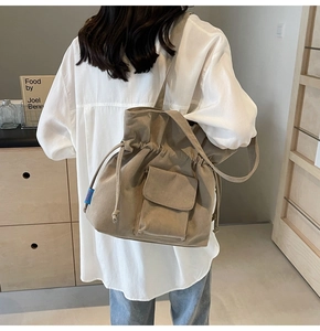 Detail of khaki corduroy drawstring tote bag with front flap pocket and blue woven label