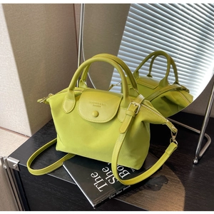 Detail of lime green nylon dumpling bag featuring dual top handles and gold-tone hardware