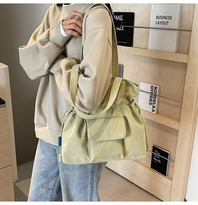 Detail of light green corduroy shoulder bag with drawstring closure and front flap pocket