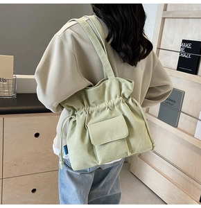 Detail of light green corduroy tote bag with drawstring closure on female model