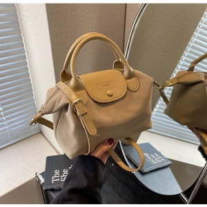Detail of beige oxford fabric dumpling bag with faux leather flap and logo branding