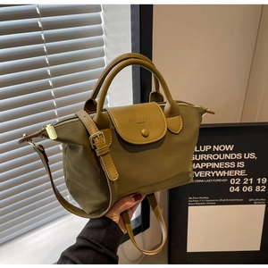 Detail of olive green nylon tote with leather handle and embossed flap in soft light