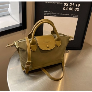 Close-up of olive green oxford fabric handbag with leather details on a metal table