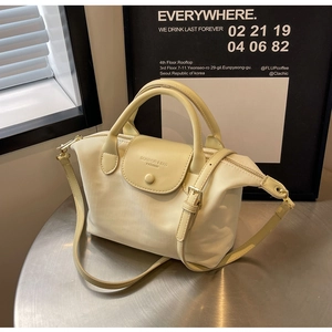 Detail of cream Oxford fabric handbag on silver table with adjustable strap and top handle