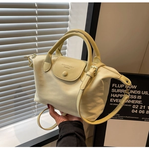 Detail view of cream oxford fabric bag featuring magnetic flap and leather handle