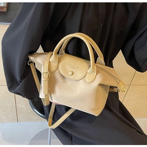 Detail of beige oxford fabric dumpling bag with leather flap and brand logo embossing