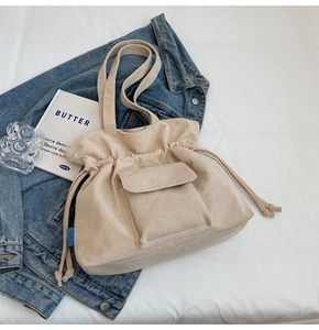 Close-up of cream corduroy tote bag showing soft ribbed texture and drawstring closure
