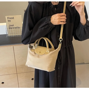Detail of beige nylon crossbody bag with leather flap and adjustable shoulder strap