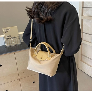 Back view of model wearing khaki nylon crossbody bag with leather handles in warm home setting