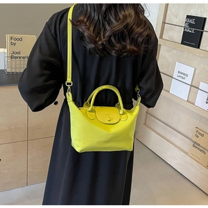 Detail view of neon green mini nylon bag with leather handles shown in cross-body style