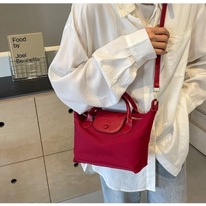 Detail of rose red nylon tote with red leather flap and adjustable long strap