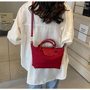 Detail of red oxford nylon handbag featuring premium leather flap and sturdy handle