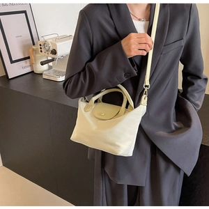 Chic cream nylon dumpling bag with leather handles shown in a lifestyle setting