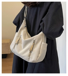 Detail of canvas hobo bag showing vertical zipper pockets and side compartment