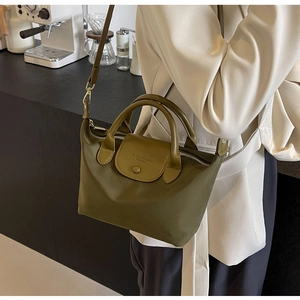 Detailed view of an olive green nylon dumpling bag with premium leather handle and strap
