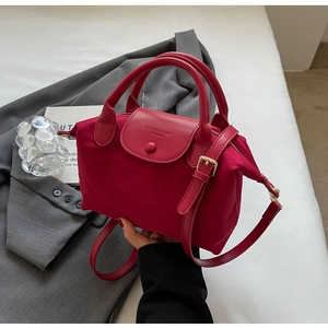Detail view of red oxford fabric tote bag with faux leather flap and golden hardware