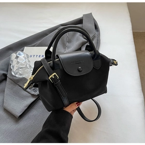 Detail of black waterproof nylon tote bag with leather flap and logo branding