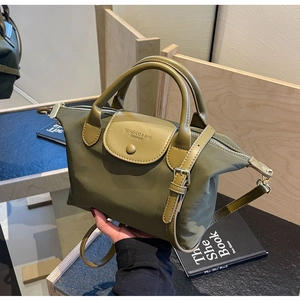 Detail of olive green nylon tote with leather handle and branded flap closure