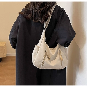 Detail of beige canvas crossbody bag featuring functional zippers and large capacity design