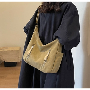 Detail of khaki canvas crossbody bag with decorative long zipper pulls and side pockets