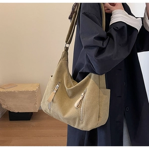 Detail of khaki canvas hobo bag with front zip pockets on model in a trench coat