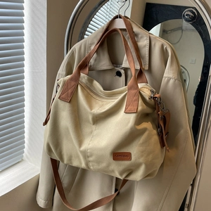 Minimalist canvas tote bag with brown straps hanging on a classic beige trench coat